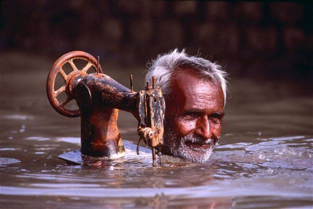 Porbandar, Gujarat 1983 - Tailor carries his sewing machine through monsoon floodwaters - Steve McCurry