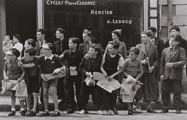 Robert Capa, 'Watching the Tour de France in front of the bicycle shop owned by Pierre Cloarec, one of the cyclists in the race, Pleyben, Brittany, France' (July, 1939)