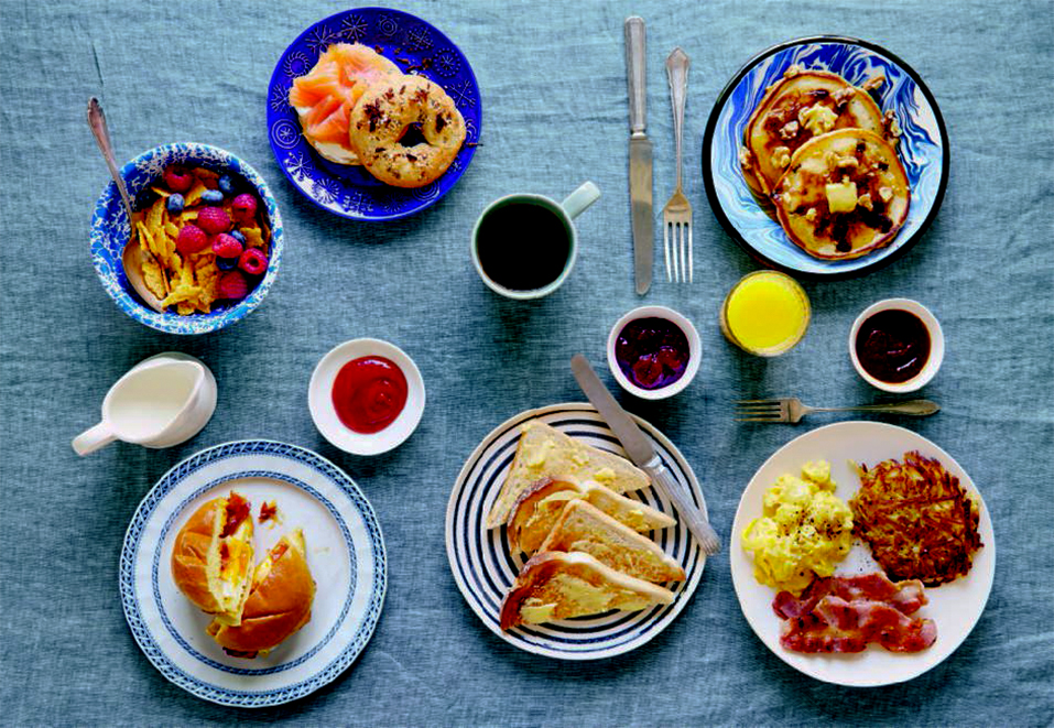 Clockwise from top left: toasted cornflakes; everything bagel with cream cheese and lox; pour-over coffee; orange juice; blueberry pancakes; the diner breakfast; diner toast; bacon, egg, and cheese sandwich, from the American breakfast pages of Breakfast: The Cookbook 